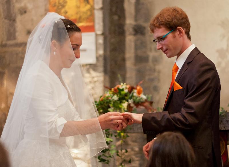 Couple marié heureux sortant de l’église sous les pétales, musique classique en fond